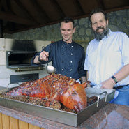 Koch Marco Müller (li.) übergießt das Spanferkel immer wieder mit dem Sud und Inhaber Jörg Schneider (re.) sorgt für die richtige Temperatur im Ofen. (Foto Beate Kierey)